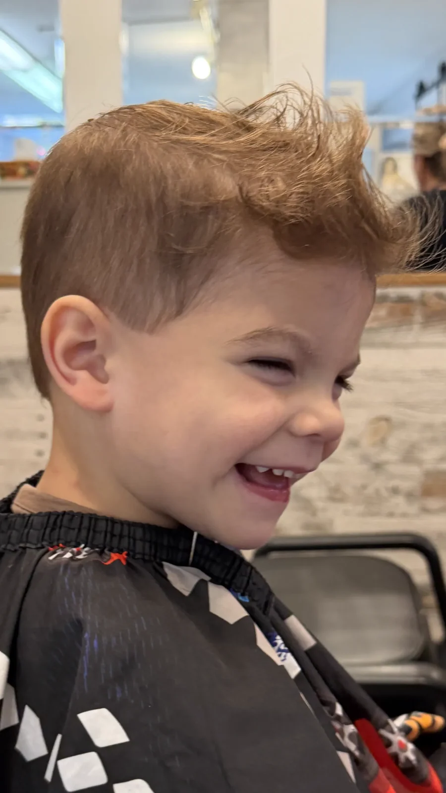 A child grinning after a haircut at Kidstyles Salon